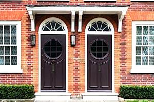 Twin Arched Dark Doors in Red Brick Wall with White Details